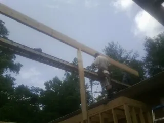 Carpenter setting a ridge beam over a new addition frame — Ice Dam Removal by Roofing Brothers in Waltham