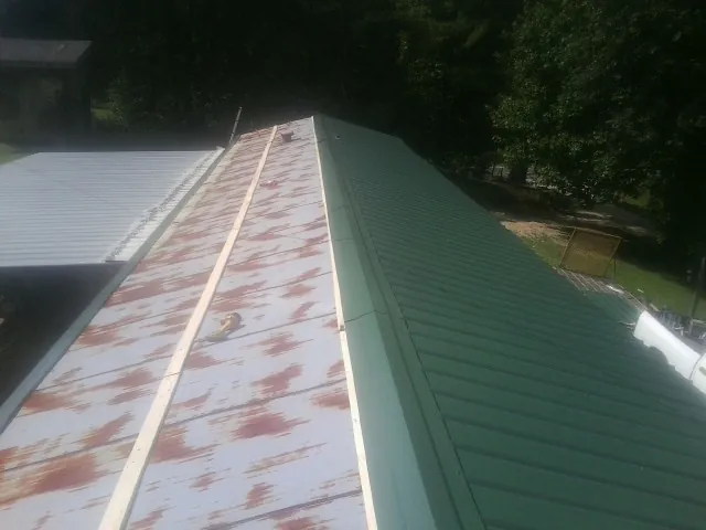 Old rusted panels beside newly installed green metal roofing — Wind Damage Roof Repair by Roofing Brothers in Waltham
