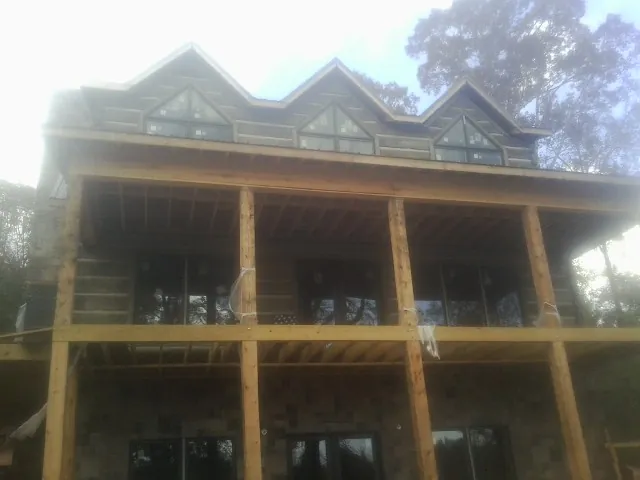 Dormers and porch framing on a large log home under construction — Roof Coating work by our crew in Waltham