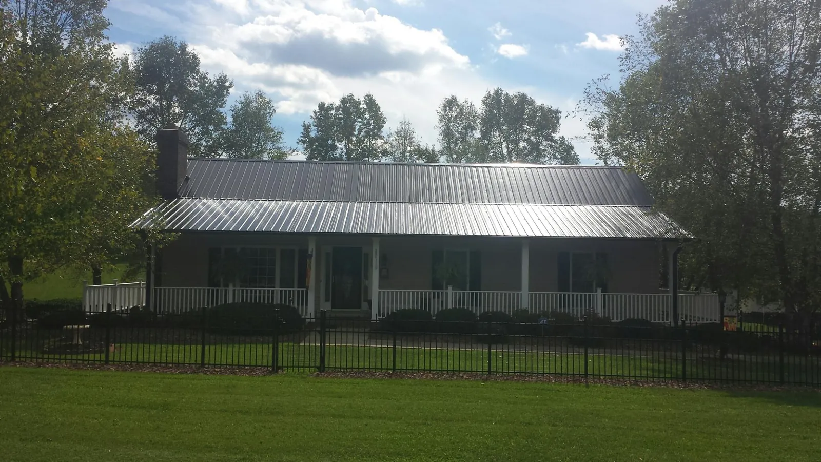 Gray metal roof on a brick ranch with a full width front porch — Gutter Guard Installation work by our crew in Waltham